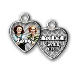 Silver-toned heart-shaped pendant with the text "Sister" and an image of two women. The reverse side has the text "You are beautiful".
