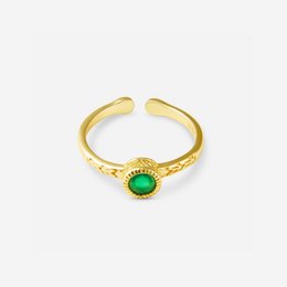 A gold-toned statement ring with a round green onyx stone, designed for bold and fashionable accessorizing.