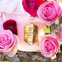 Tall, round, pink and red scented candle with rose, ylang ylang, and cinnamon fragrance.