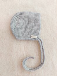 Soft, cozy greige merino wool bonnet hat for babies. Features a classic knit design and a sweet bow detail.