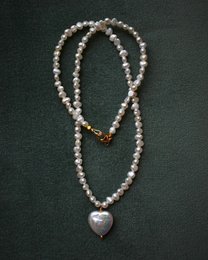 A delicate pearl necklace with a heart-shaped pendant, featuring a string of small pearls and a larger pearl at the center.