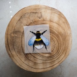 Iron-on patch with a colorful bumblebee design. Features a round, fuzzy bumblebee with black, yellow, and blue coloring.