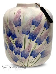Tall ceramic vase with a floral design featuring purple and blue flowers, likely lavender or muscari. The vase has a cylindrical shape and a textured surface.