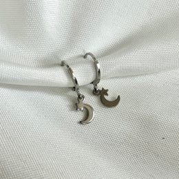 Silver hoop earrings with a moon and star charm.