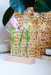Wooden holder with bottle for picking flowers. Vase with yellow flowers, green leaves, and wooden accents. Rustic, natural style.
