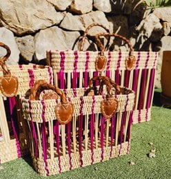 Woven purple and pink handbag with woven handles and decorative accents.