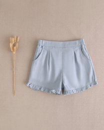 Blue girls' denim shorts with a ruffled hem, available in sizes 3 years to 12 years. Casual and comfortable style for everyday wear.