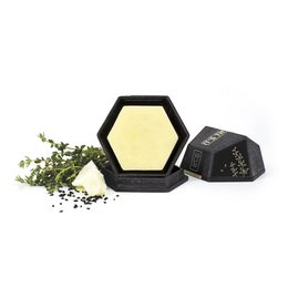 Solid body butter in a hexagonal black container, with a yellow center containing thyme leaves and peppercorns. The product is labeled "IT'S THYME".