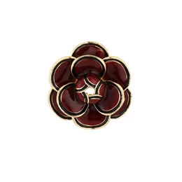 Red flower brooch with dark burgundy petals, gold-tone metal setting, circular floral design