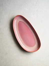 Oval-shaped pink serving tray made of ceramic material.