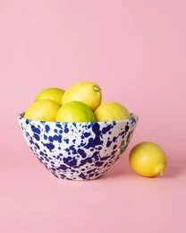 Ceramic salad bowl in yellow color, containing a fresh salad with red and green leaves, sliced red fruits, and other ingredients.