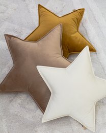 Decorative star-shaped velvet pillows in various colors including mustard, beige, and mint. The pillows have a plush, soft texture and are suitable for use in a child's bedroom or nursery.