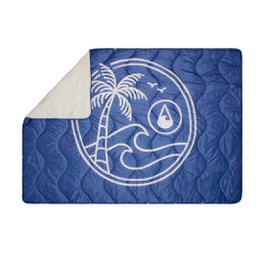  A large, quilted picnic blanket in a deep blue color with a white graphic design featuring a palm tree, waves, and a sun. The blanket appears to be made of a soft, durable material and is suitable for outdoor use.