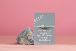  A silver-colored bracelet with a natural crystal stone accent, featuring a minimalist design and a simple text description.