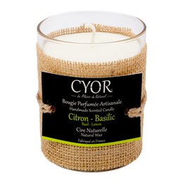A round, tall candle with a natural lemon and basil scent, encased in a glass container with a burlap-style wrap.