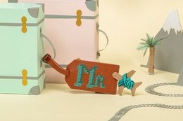 Brown leather luggage tag with embroidered 'Aloha' text and tropical design elements.
