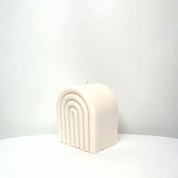Tall, round, vegan soy wax candle in pearl, rosy, and peach colors with an arc-shaped design.
