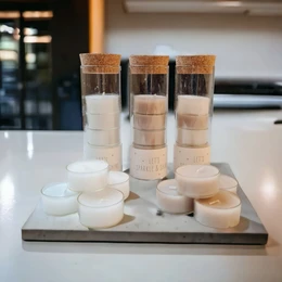 Glass tea light holders in white and stone colors, containing tea light candles.