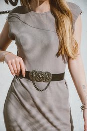 Sleek black leather belt with ornate metal buckle and chain detail, suitable for casual or formal wear.