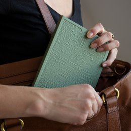 A minimalist, hardcover notebook with a textured cover in shades of blue. The notebook features blank pages and a simple, elegant design.
