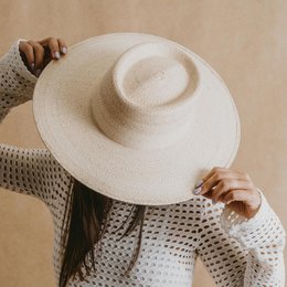  A wide-brimmed, off-white straw hat with a textured weave pattern and a simple, minimalist design.