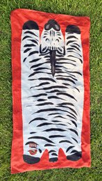  Zebra-patterned beach towel with a playful design featuring a large zebra face and paws. Made of soft, absorbent material suitable for the beach or pool.
