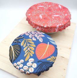 Small, adaptable food wrap cover with floral pattern. Made of flexible material to fit various container sizes.