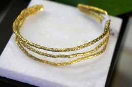 Gold-plated brass cuff bracelet with pine branch design, available in gold and gold-black variants.