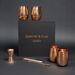 Hammered copper cocktail cups in a set of 4, with a 6-piece accessory set. The cups have a capacity of 470 ml and feature a unique hammered texture for a rustic, artisanal look.