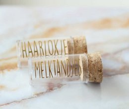 Gold and black baby tooth and hair lock tubes for keepsake storage.