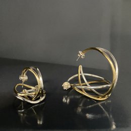 Elegant bi-metal wave hoop earrings with a modern, abstract design featuring a mix of gold and silver tones.