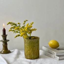  Handmade ceramic bud vase in an ochre color, suitable for holding a single flower or small bouquet. The vase has a simple, cylindrical shape and a textured, earthy appearance.