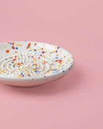 Handmade ceramic plate grater with a multicolor carnival design. Features a round shape and vibrant colors including orange, yellow, and blue.