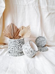  White speckled ceramic plant pots with natural dried palm leaf decorations, modern minimalist style.