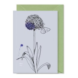 Greeting card with a hand-drawn illustration of a purple flower and the text "Good Luck" on a light gray background. The card comes with a green envelope.