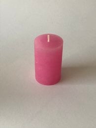 A short, cylindrical pink candle with a smooth, uniform surface.
