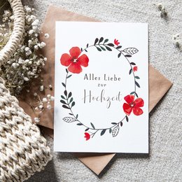 Folding card with a floral wreath design, featuring red flowers and leaves. The text on the card says "Alle Liebe zur Hochzeit" which means "All the love for the wedding" in German.