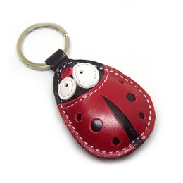 A cute, handmade leather keychain in the shape of a ladybug with a red body and black spots.