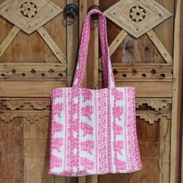 A pink and turquoise block print shoulder bag with a floral pattern and pleated texture.