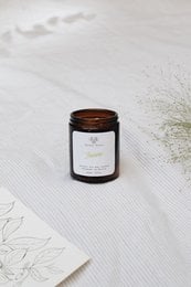 A tall, round jasmine-scented candle available in 120ml, 180ml, and 500ml sizes. The candle has a simple, minimalist design with a black glass container and a wooden lid.