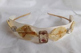 Beige and gold headband with decorative stones and bows.