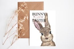 Postcard with a realistic illustration of a bunny, featuring the text "Bunny Easter" on a beige background with floral accents. The postcard is available with or without an envelope.