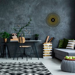 A modern, minimalist wall lamp with a wire frame and a sunflower-inspired design. The lamp features a sleek, black metal frame and a warm, yellow light source that creates a cozy ambiance.