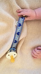 Blue floral patterned pacifier clip with yellow duck charm, fabric strap attachment