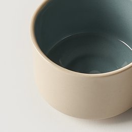 Ceramic mug in beige and blue colors, with a simple, minimalist design.