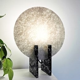 A round, white table lamp with a textured, globe-shaped shade and a black metal base.