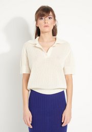  Short-sleeved cashmere polo shirt in ecru white with pointelle knit detail, paired with a navy blue midi skirt with a thigh-high slit.
