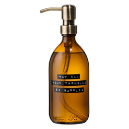 Hand soap in a brown glass bottle with a brass pump. The bottle has a label that says "may all your troubles be bubbles". The soap is made of bamboo and has a natural, earthy color.