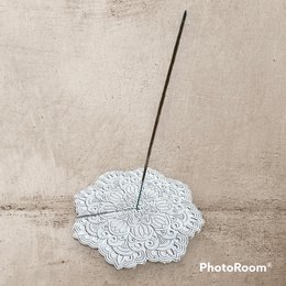 Mandala coaster or incense holder made of Jesmonite, featuring a round, intricate floral design in a neutral color.