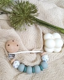 Newborn pacifier clip with dinosaur design, made of soft, durable materials in neutral colors.